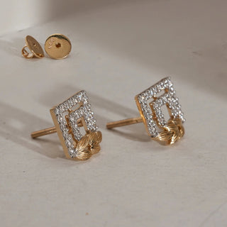 Angled view of Art Deco Statement Diamond Stud Earrings on soft beige background. Made in 14KT hallmarked yellow gold with layered diamond-studded square frames and golden leaf motif. EF colour, VVS clarity lab grown diamonds total 0.46 carats. Earrings weigh 2.913 grams, secured with Bombay screw closure.