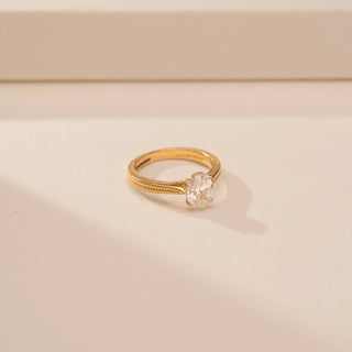 Side view of a 14KT Yellow Gold diamond ring with an oval centre diamond and textured braided shoulders.