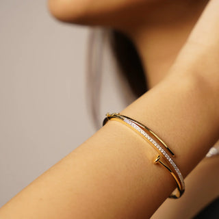 Slim curved bangle bracelet featuring a row of small round-cut diamonds set along one side, paired with a smooth polished band for a minimal and elegant look.