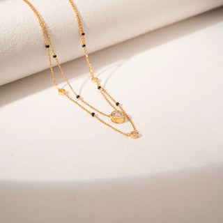 Top view of 14KT Yellow Gold layered diamond mangalsutra featuring bezel-set round diamonds and black bead accents.