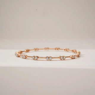 Front view of Rose Gold Duo Diamond Bangle, featuring paired round lab-grown diamonds spaced along a slender rose gold band, creating a rhythmic geometric design on a neutral surface.
