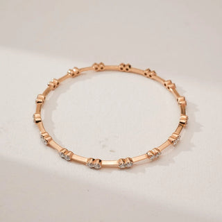 Top view of Rose Gold Duo Diamond Bangle, showcasing paired round lab-grown diamonds set at intervals along a slender rose gold band, forming a balanced circular design on a neutral surface.