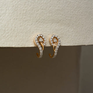 Side view of diamond swirl hoop earrings in 14KT Yellow Gold, featuring pavé-set lab-grown diamonds in an open teardrop design. Captured against a beige backdrop, highlighting graceful sparkle.