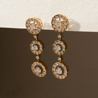 Side view of diamond floral drop earrings in 14 KT Yellow Gold, featuring three cascading flower-inspired diamond clusters with scalloped halos against a neutral backdrop.
