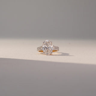 Front view of Oval Solitaire Diamond Ring in 14KT Yellow Gold, featuring a centred oval lab grown diamond with a double pavé-set band. Set on a beige backdrop, the design highlights brilliance and elegance.
