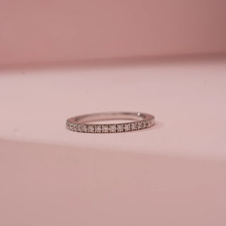 Front view of Reia’s 14 KT White Gold Minimal Glow Diamond Band. The half-eternity band features a seamless pavé row of diamonds, shown lying on a pink surface with soft lighting.