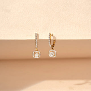 close up view of round-cut lab-grown diamond drop earrings in 14 KT white gold, featuring pavé-set diamond bar drops with cushion-shaped diamond halo charms and cushion-cut centre diamonds in an elegant design.