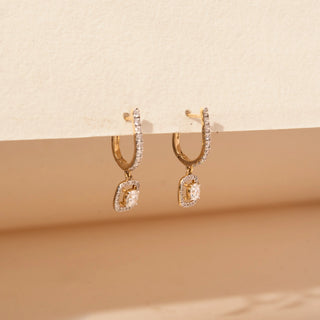 side view of round-cut lab-grown diamond drop earrings in 14 KT rose gold, featuring pavé-set diamond bar drops with cushion-shaped diamond halo charms and cushion-cut centre diamonds in an elegant design.