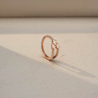 Angled view of a rose gold ring featuring a three-stone pear-cut diamond cluster, accented by a split pavé diamond band for a delicate and contemporary design.
