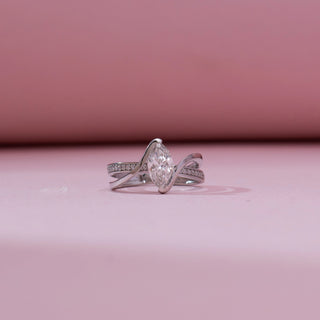 Front view of 14KT white gold bypass ring featuring a marquise-cut centre diamond with a flowing double band, one pavé-set with round diamonds.