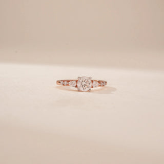 Front view of a 14KT Rose Gold diamond ring with a round centre diamond and tapered side diamonds.