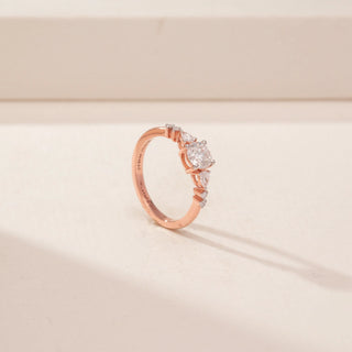Angled view of a 14KT Rose Gold diamond ring with a round centre diamond and tapered side diamonds.