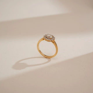 Side view of Reia’s 14 KT Yellow Gold Classic Aura Diamond Halo Ring. Captured against a cream backdrop, the symmetrical layout highlights the elevated setting and brilliant profile.