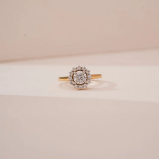 Front view of Reia’s 14 KT Yellow Gold Classic Aura Diamond Halo Ring. Captured against a cream backdrop, the layout highlights the captivating centrepiece and radiant, luxurious finish.