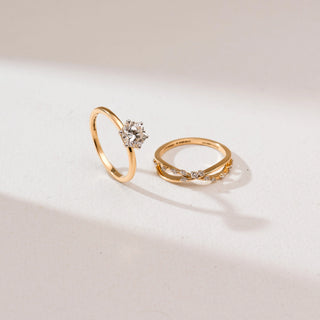 Angled view of Radiant Golden Cross Diamond Ring set in 14KT Yellow Gold, showcasing a round solitaire ring and matching cross-over pavé diamond band, displayed side by side on a soft neutral backdrop.