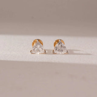 Front view of diamond stud earrings in 14KT yellow gold, featuring trilliant-cut diamonds in prong settings, displayed on a beige surface highlighting clean geometry and brilliant sparkle.
