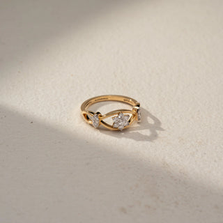 Top view of a floral diamond ring in 14 KT Yellow Gold, featuring a cluster of round lab-grown diamonds nestled within an eye-shaped openwork motif and accented by marquise-cut side diamonds, displayed against a beige backdrop.