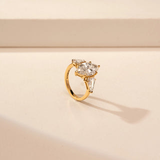 Angled view of a 14KT Yellow Gold diamond ring with a marquise centre diamond, pear-shaped side diamonds and baguette accents.