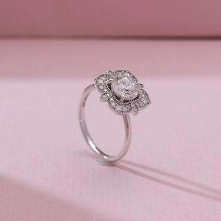 Angled view of Vintage Square Halo Diamond Ring in white gold, showcasing a round lab-grown diamond framed by an ornate square halo with intricate diamond accents, set against a soft pink backdrop.