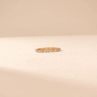 Front view of a 14KT yellow gold ring featuring baguette and round-cut diamonds, set against a beige background.