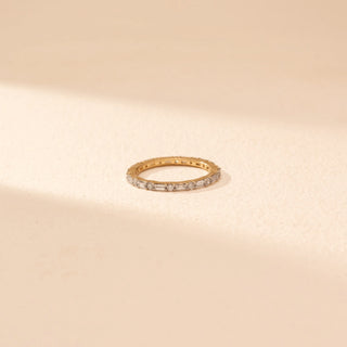 Top view of a 14KT yellow gold ring featuring baguette and round-cut diamonds, set against a beige background.