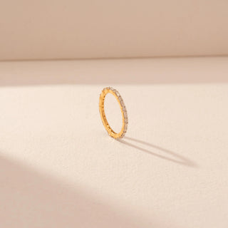 Angled view of a 14KT yellow gold ring featuring baguette and round-cut diamonds, set against a beige background.