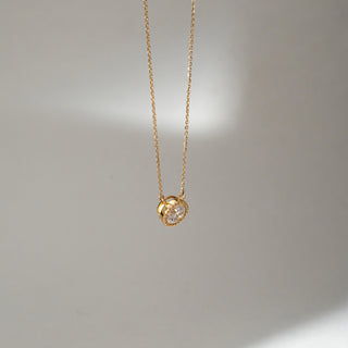 Angled view of Round Bezel Diamond Pendant Necklace in 14KT Yellow Gold, featuring a centred round lab grown diamond in a textured bezel setting. Set on a neutral backdrop, the design highlights depth and refined brilliance.
