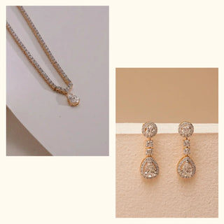Pear-shaped lab-grown diamond pendant necklace paired with drop earrings by Réia, displayed as a flat lay and front-facing product view, highlighting pavé detailing on soft neutral surfaces in warm light.