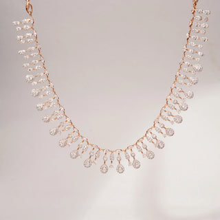 Front view of a teardrop lab-grown diamond necklace in 14KT Rose Gold, featuring cascading pear-shaped diamond drops in an elegant fringe design. Captured against a beige backdrop, the graceful silhouette radiates brilliance.