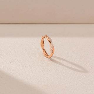 Angled view of an intertwined diamond ring in 14KT rose gold, featuring pavé-set diamonds and a graceful crossover design.