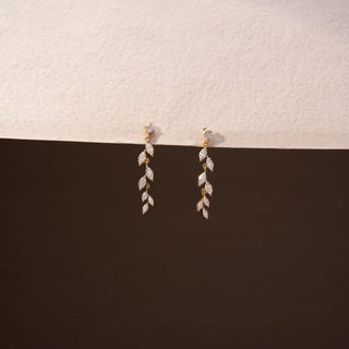 Front view of diamond drop earrings in 14 KT Yellow Gold, featuring cascading marquise-shaped diamond motifs suspended from delicate diamond studs against a neutral backdrop.
