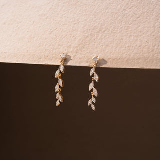 Side view of diamond drop earrings in 14 KT Yellow Gold, featuring cascading marquise-shaped diamond motifs suspended from delicate diamond studs against a neutral backdrop.
