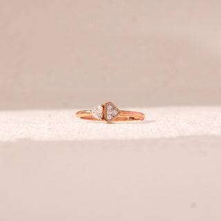 Front view of geometric diamond ring in rose gold, featuring a round lab-grown diamond paired with a triangle-shaped cluster. Placed on a soft beige surface, the design reflects modern contrast and balance.
