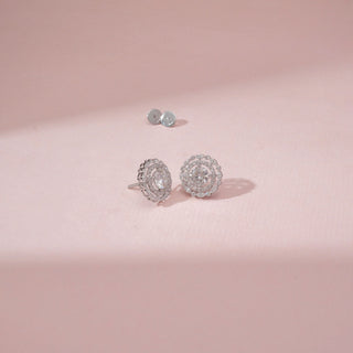 Angled view of a 14KT White Gold diamond stud earrings, featuring round diamonds in a floral halo setting.