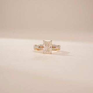 Front view of a 14KT Yellow Gold diamond ring, featuring an emerald-cut centre diamond and diamond-set split shoulders.