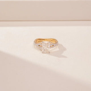 Close up view of a 14KT Yellow Gold diamond ring, featuring an emerald-cut centre diamond and diamond-set split shoulders.