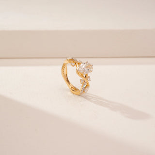 Angled view of a 14KT Yellow Gold diamond ring, featuring an oval centre diamond and floral diamond-set shoulders.