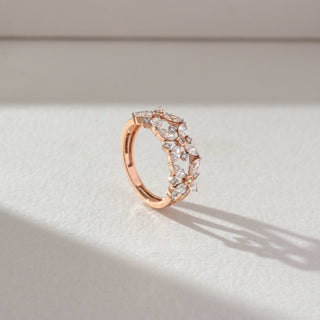 Side angled view of floral diamond band ring in rose gold, featuring marquise-shaped lab-grown diamonds forming intricate flower motifs. Captured against a soft beige textured background.