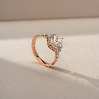 Angled view of a princess halo engagement ring in 14 KT White Gold, featuring a princess-cut lab-grown diamond framed by a sparkling halo and accented by a diamond-set band, displayed against a beige backdrop.