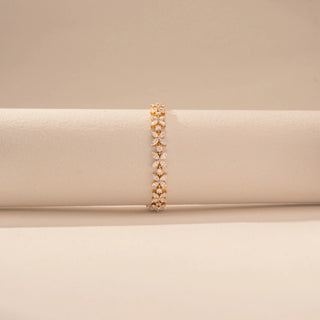 Front view of a 14KT dual gold bracelet featuring marquise-cut diamonds in a floral design, set against a beige background.