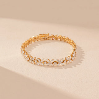 Top view of a 14KT dual gold bracelet featuring marquise-cut diamonds in a floral design, set against a beige background.