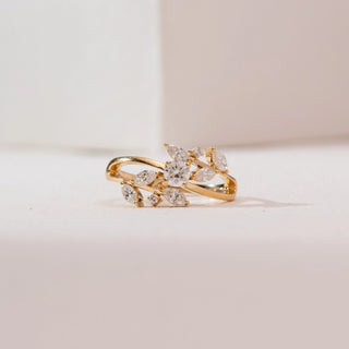 Front angle view of a 14KT yellow gold leaf-inspired diamond ring featuring marquise-shaped diamonds and a round center stone in an open, flowing crossover design on a polished band.