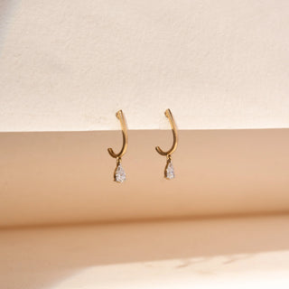 close up view of pear-shaped lab-grown diamond drop hoop earrings in 14 KT rose gold, featuring sleek polished hoops with delicate pear-cut diamond drop charms in a timeless minimalist design.