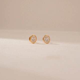 Front view of a 14KT Yellow Gold diamond stud earrings, featuring oval diamonds in a bezel setting.