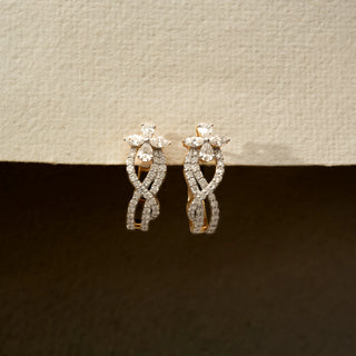Front view of floral diamond hoop earrings in 14 KT Yellow Gold, featuring intertwined pavé-set curves with marquise and pear-shaped diamond accents against a neutral backdrop.
