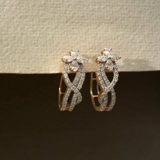 Side view of floral diamond hoop earrings in 14 KT Yellow Gold, featuring intertwined pavé-set curves with marquise and pear-shaped diamond accents against a neutral backdrop.

