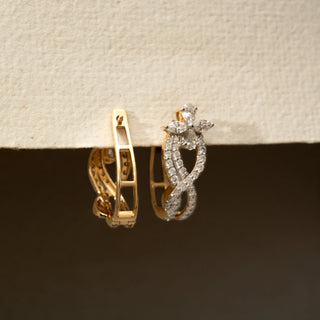 Angled view of floral diamond hoop earrings in 14 KT Yellow Gold, featuring intertwined pavé-set curves with marquise and pear-shaped diamond accents against a neutral backdrop.
