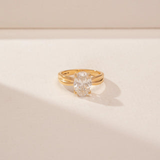 Close up view of a 14KT Yellow Gold diamond ring, featuring an oval-cut centre diamond and a double-band design.