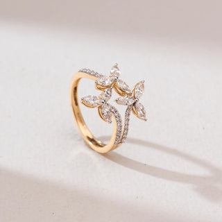 Angled view of a 14KT yellow gold triple marquise floral diamond ring with three flower motifs of marquise-cut diamonds and a curved pavé diamond band on a soft neutral background.