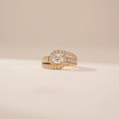 Close-up view of a 14KT Yellow Gold diamond ring, featuring a round centre diamond and diamond-set crossover bands.